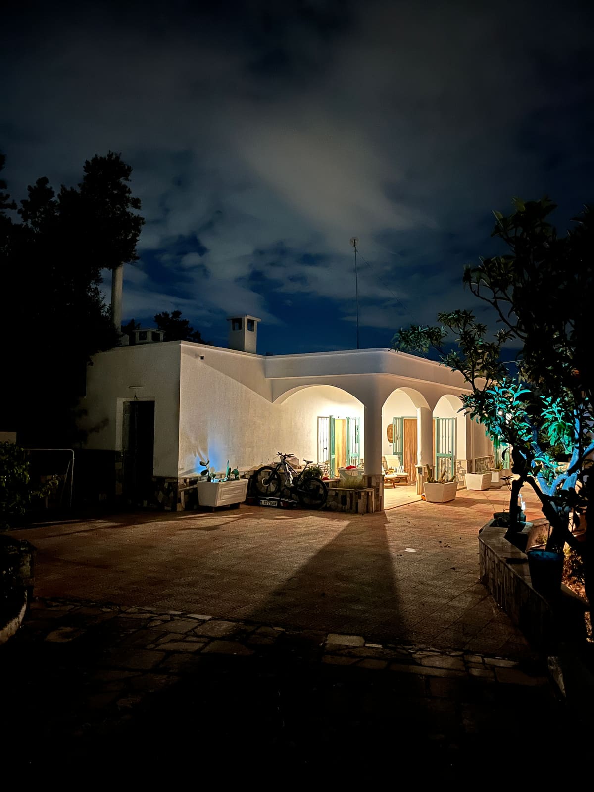 The lit arches of the house against the ink-blue evening sky